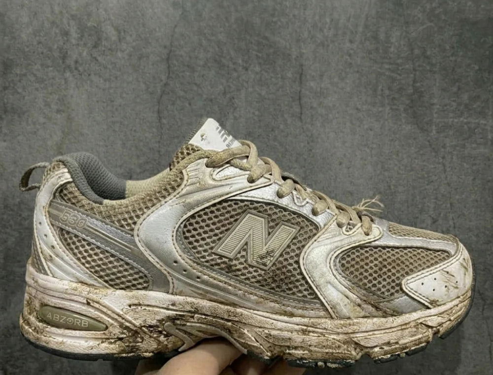 A heavily soiled white trainer before washing