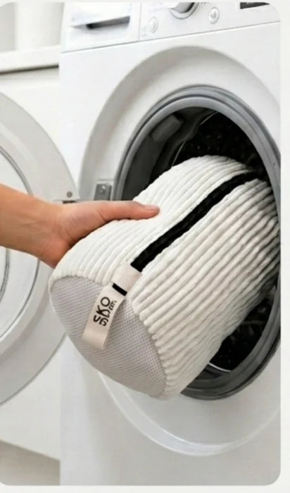The closed wash bag being placed into a washing machine drum