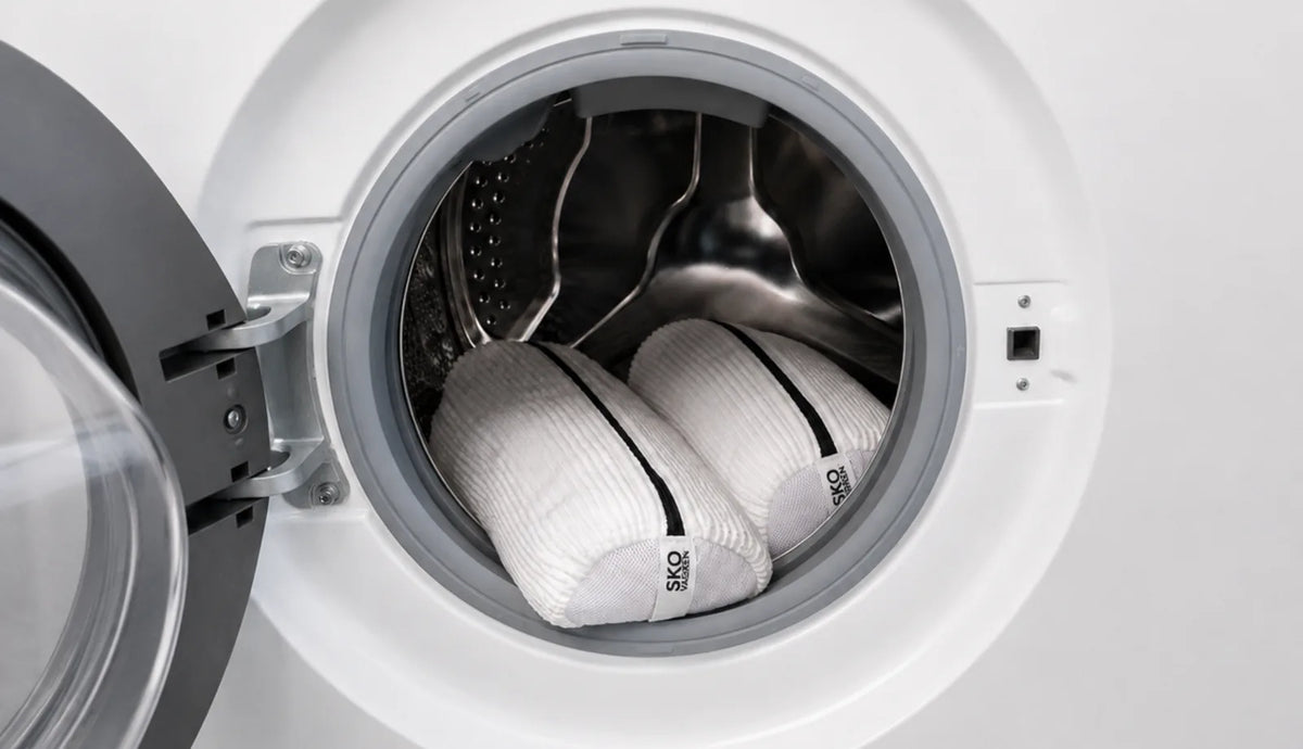 Two Skovasken wash bags holding trainers inside an open washing machine drum